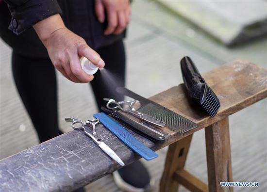A volunteer barber disinfects tools at a community in southwest China's Chongqing Municipality, Feb. 16, 2020. Since the outbreak of the novel coronavirus, most barbershops have been closed. A community in Beibei District of Chongqing organized a team of volunteer barbers to provide free haircuts for its residents. (Xinhua/Liu Chan)